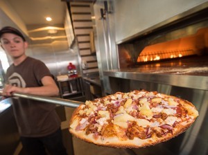 Elyse Doyle-Martinez, supervisor of the PizzaRev restaurant in Oxnard, places a pizza in the oven. Westlake Village-based PizzaRev is expanding across the country with 27 franchise deals currently in the works. (Nik Blaskovich / Business Times photo)