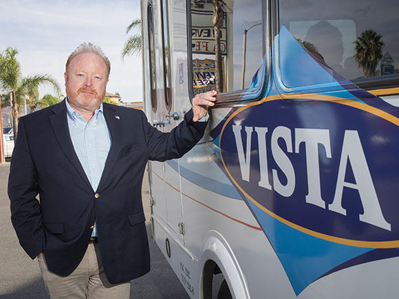 Chap Morris, owner of bus service Fillmore Area Transit Corp., stands alongside one of the company’s buses. After 40 years in business, the firm will shutter by February. (Nik Blaskovich / Business Times photo)