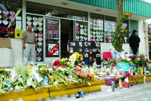 Sam Hassan, owner of Isla Vista Deli Mart, stands before a memorial for Christopher Martinez, a UCSB student who was shot dead inside the store during the May 23 shooting last year. Five other UCSB students were also killed, along with the shooter. (File Photo)