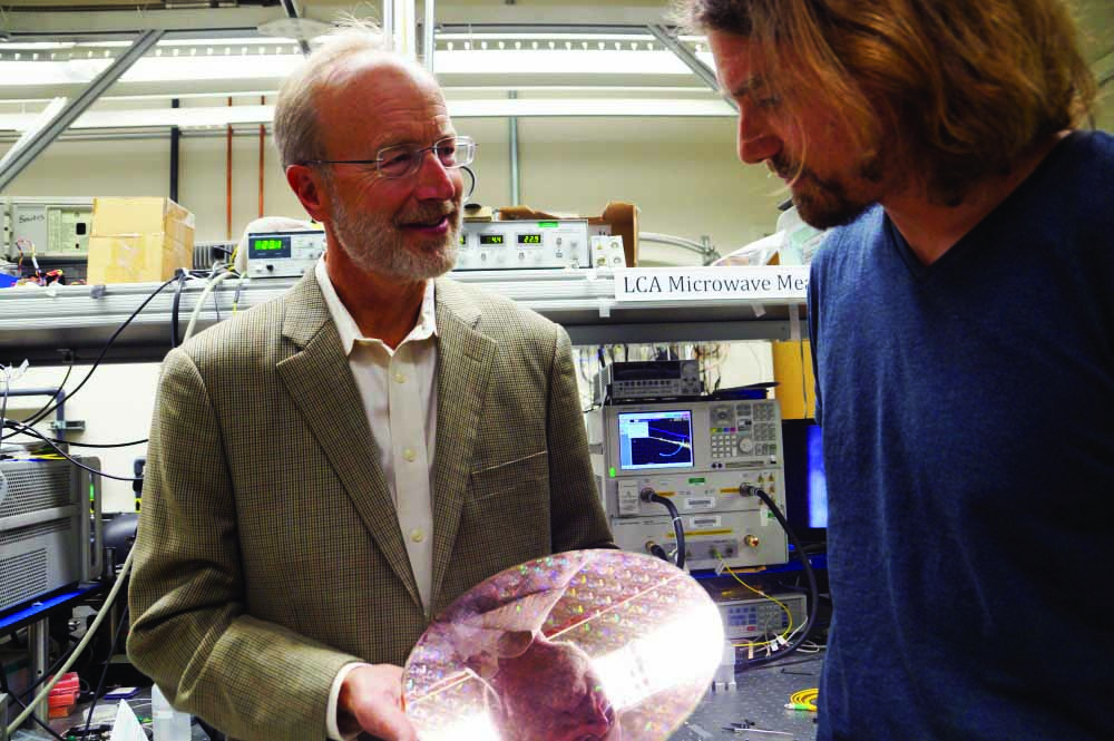 John Bowers and researcher Tin Komljenovic with a wafer of integrated photonic circuitry to be developed by AIM.